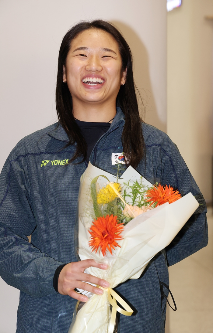 ▲ アジアの頂点に立ち、メジャー大会グランドスラムの偉業を成し遂げた世界バドミントン女子シングルスの“絶対的強者”アン・セヨンが13日、仁川国際空港第2ターミナルから帰国し花束を受け取り笑顔を見せている。 ⓒ연합뉴스