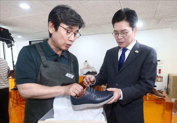 \"チョン・ウォノ（共に民主党・ソウル市長候補）が24日午後、ソウル・城東区のアンダースタンドアベニューで開かれた聴覚障害者手作り靴ブランド「アジオ」の店舗オープン行事に出席し、1日アルバイトとして参加したユ・シミン作家から靴を受け取っている。