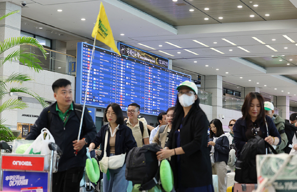 \"仁川国際空港の入国場でガイドの案内を受けながら移動する外国人団体観光客\"