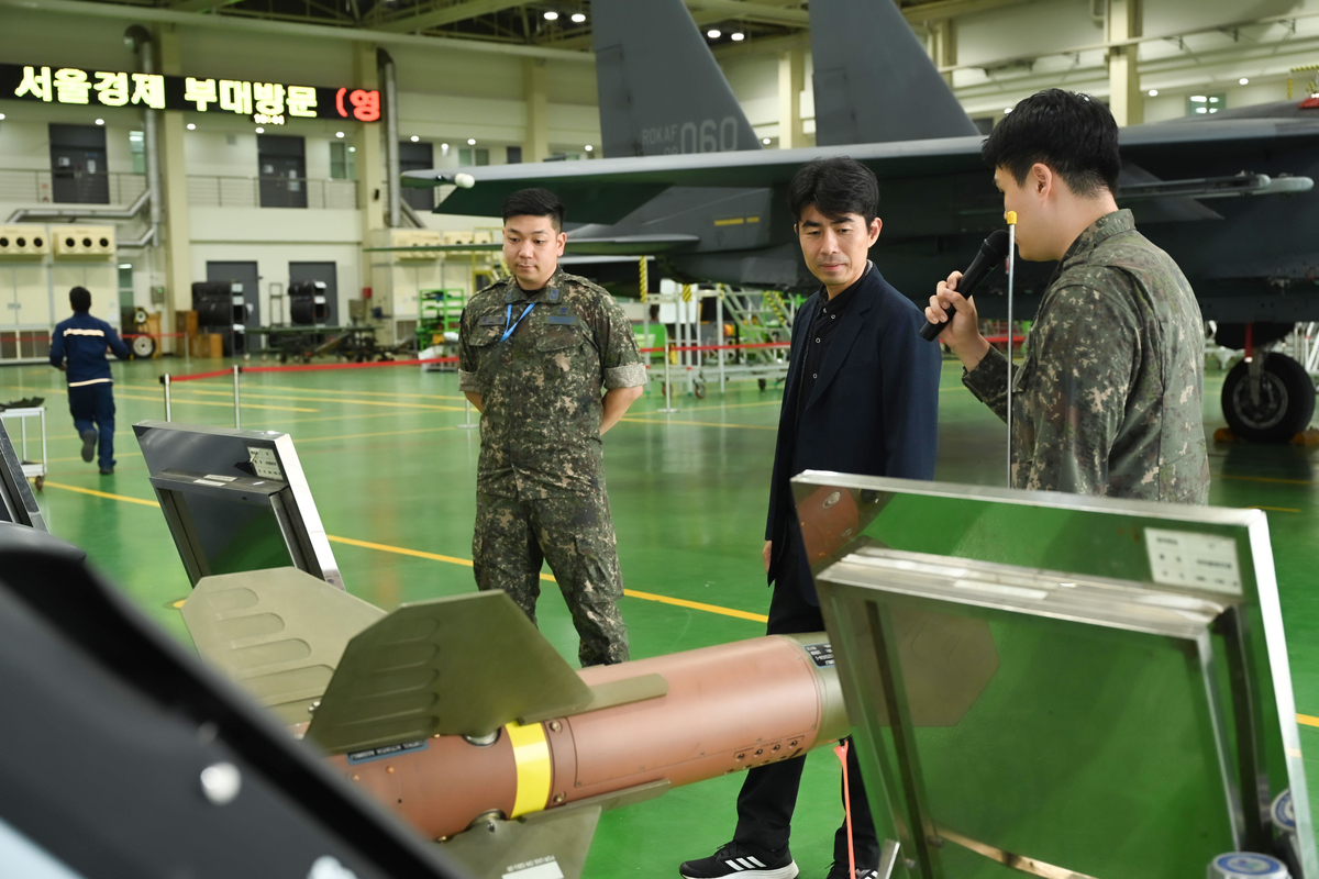 \"7日、大邱にある空軍第11戦闘飛行団でイ・ヒョンホ記者がF-15K戦闘機の脇で装着された武装について説明を受けている。写真提供=空軍\"