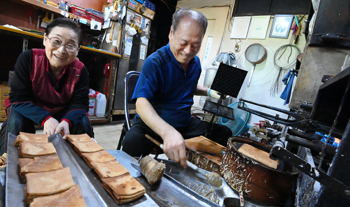 \"母の日を二日後に控えた6日に、仁川中区の老舗『インチョンダン』でカン・ドンギ氏とピョ・ヨンヘ氏夫妻が焼きたての「ピーナッツ菓子」を冷ます板に移し、笑顔を見せている。撮影＝クァク・ソンホ記者　仁川＝チ・ゴンテ記者\"
