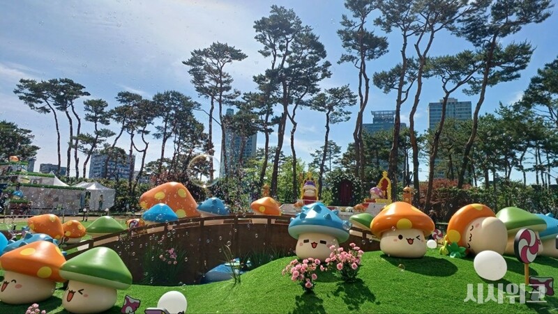\"ロッテワールドタワー前にあるワールドパークの芝生広場は、『メイプルストーリー』のゲーム内背景であるヘネシスに生まれ変わった。