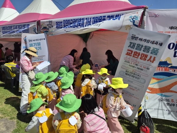第68回ミリャンアリラン大祭期間中に行われた「リサイクル品交換イベント」で、子どもたちが持参した廃乾電池と牛乳パックを新しい電池と再生トイレットペーパーに交換している。（写真＝ミリャン市）